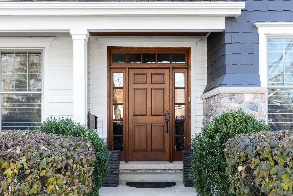 Wooden front door with surrounding greenery.