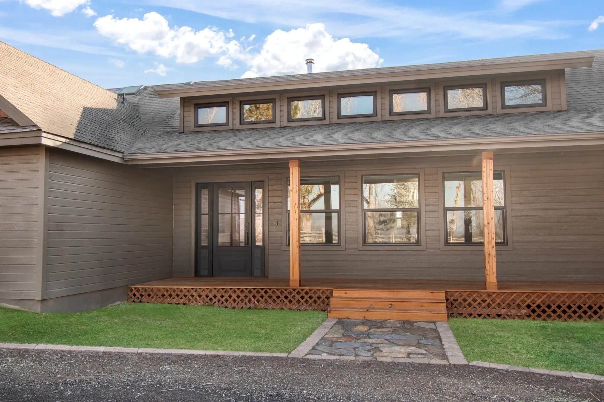 Wooden house with porch and multiple windows.