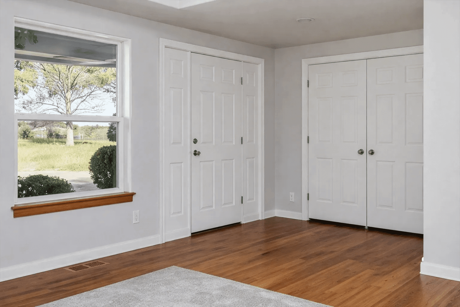 Empty room with window and closet doors.