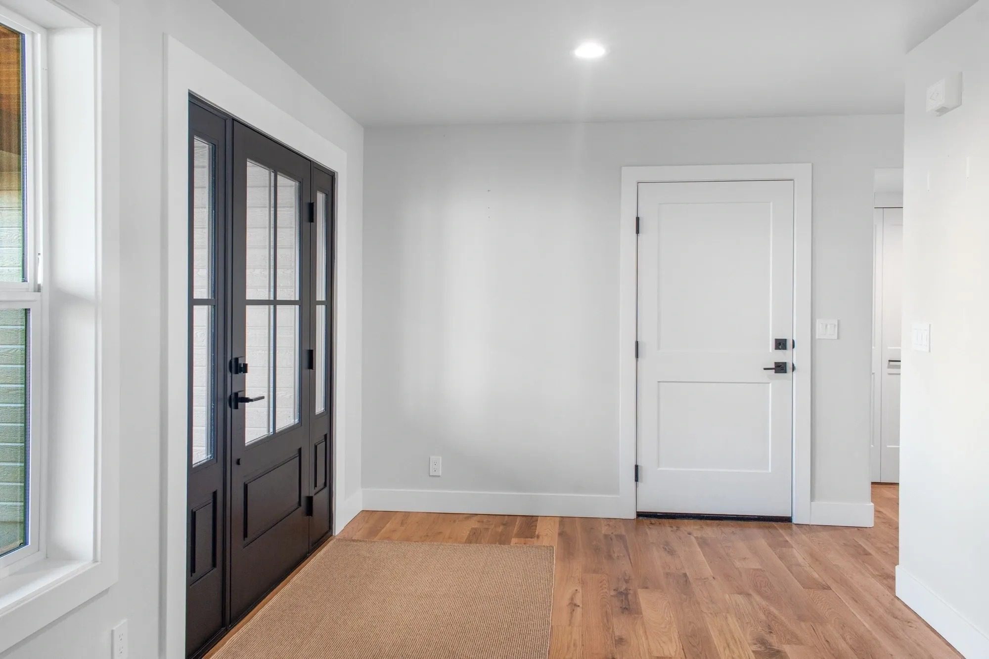 Modern entryway with wooden floor and doors.