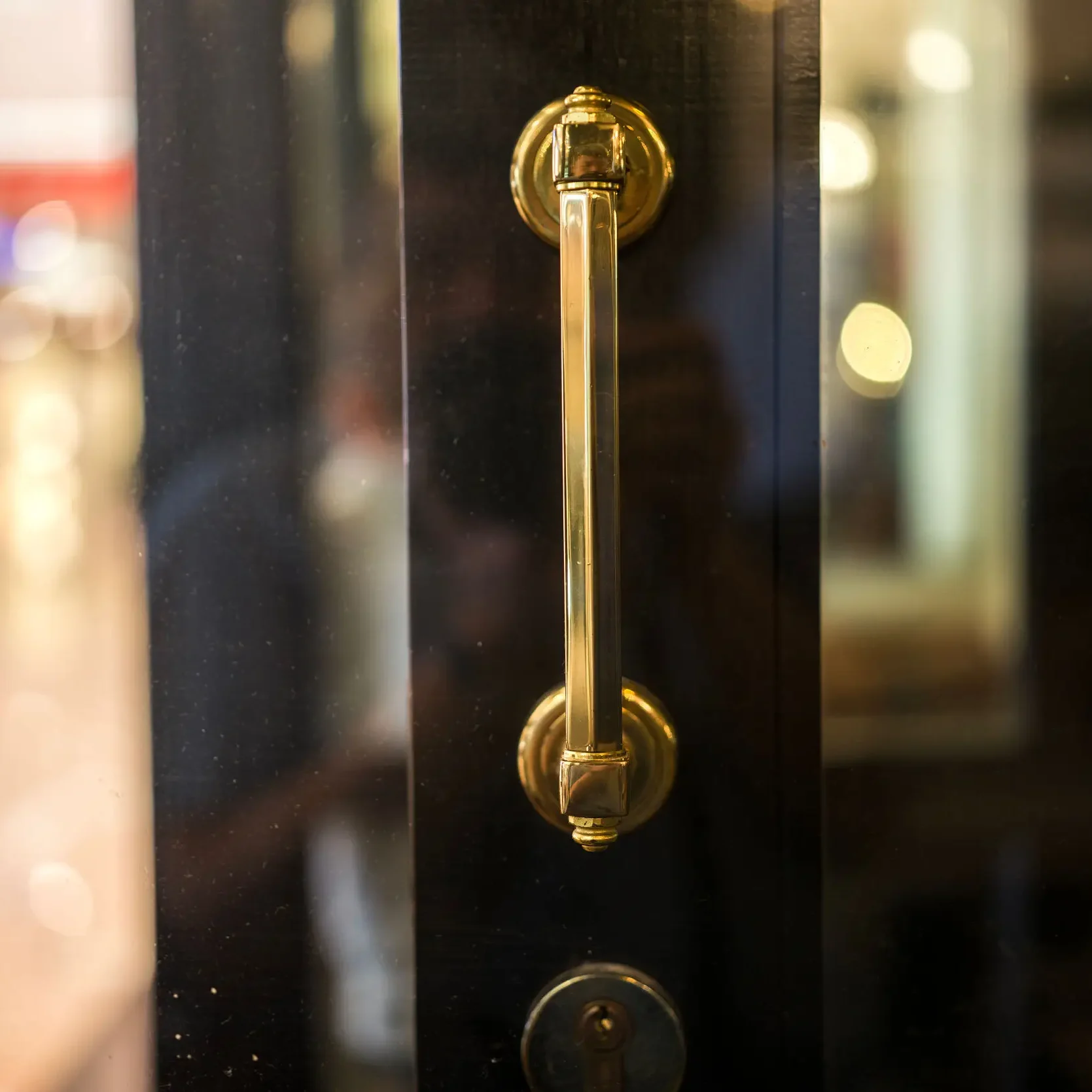 Close-up of a brass door handle on a glass door.